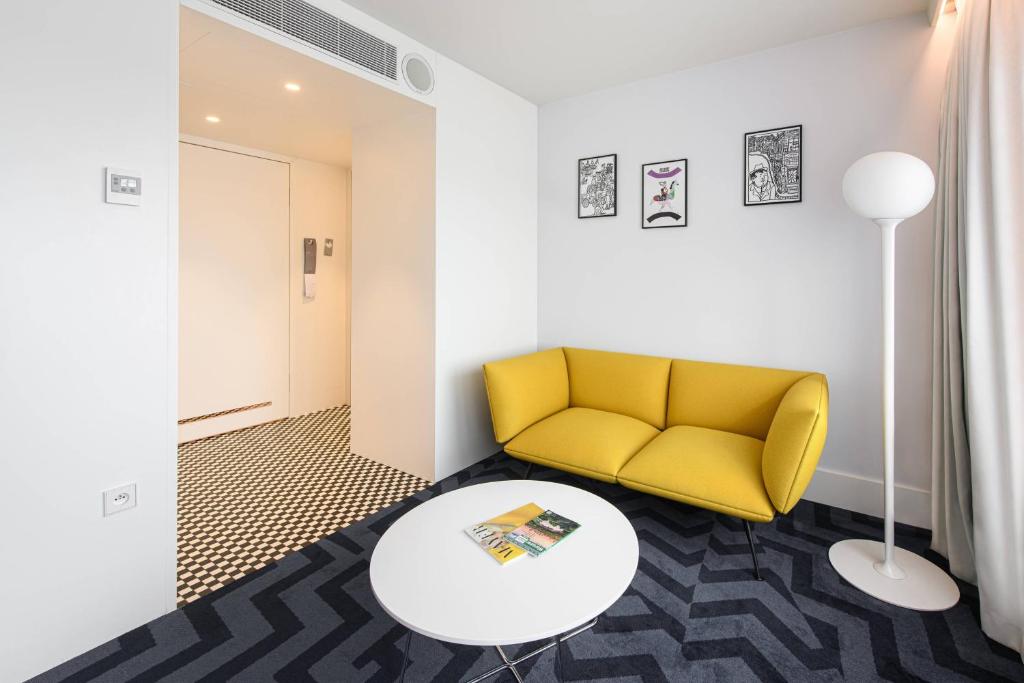 a living room with a yellow couch and a table at Renaissance Warsaw Airport Hotel in Warsaw