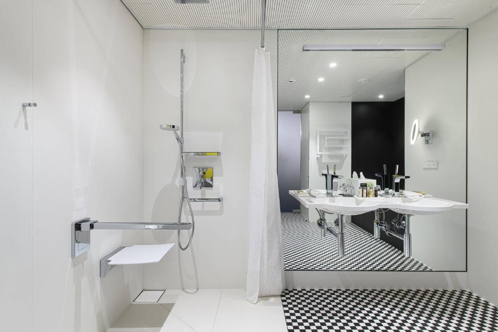 a white bathroom with a shower and a sink at Renaissance Warsaw Airport Hotel in Warsaw