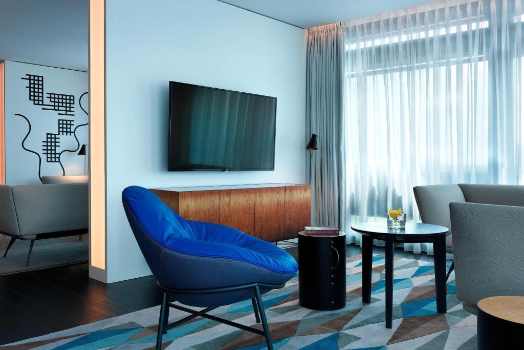 a living room with a blue chair and a tv at Renaissance Warsaw Airport Hotel in Warsaw