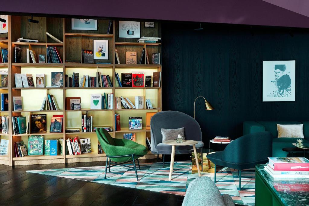 a room with two chairs and a book shelf with books at Renaissance Warsaw Airport Hotel in Warsaw