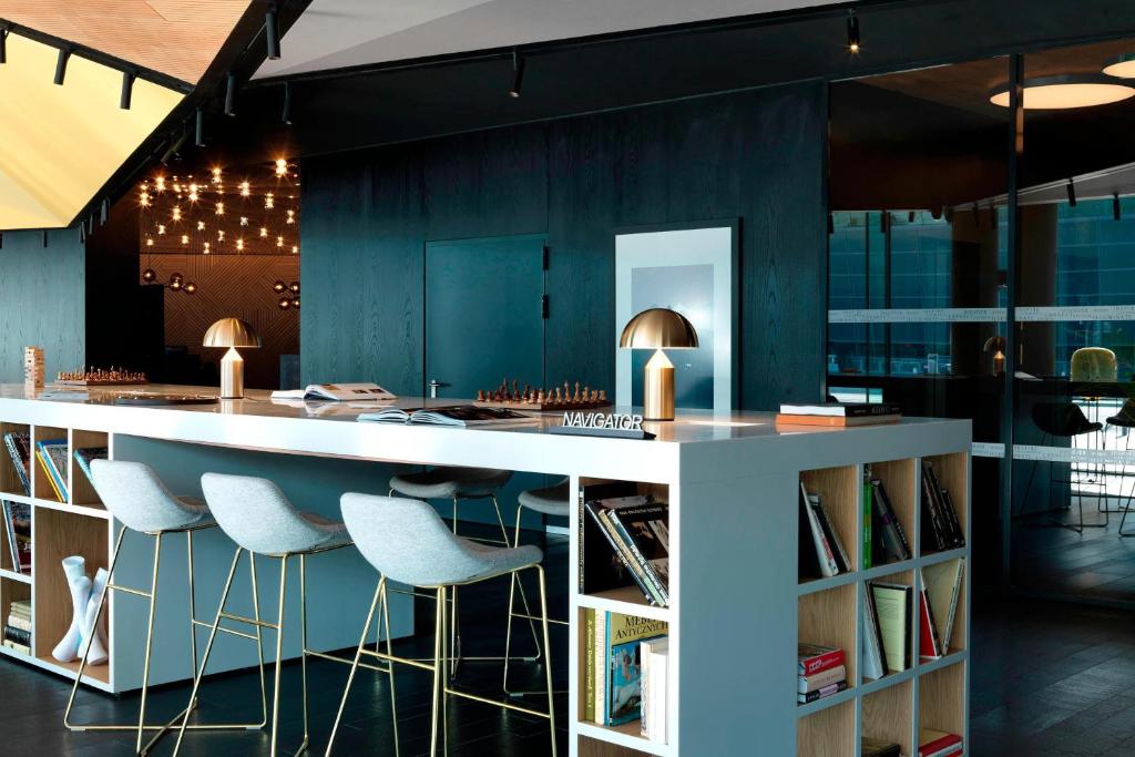 a kitchen with a white counter and stools at Renaissance Warsaw Airport Hotel in Warsaw