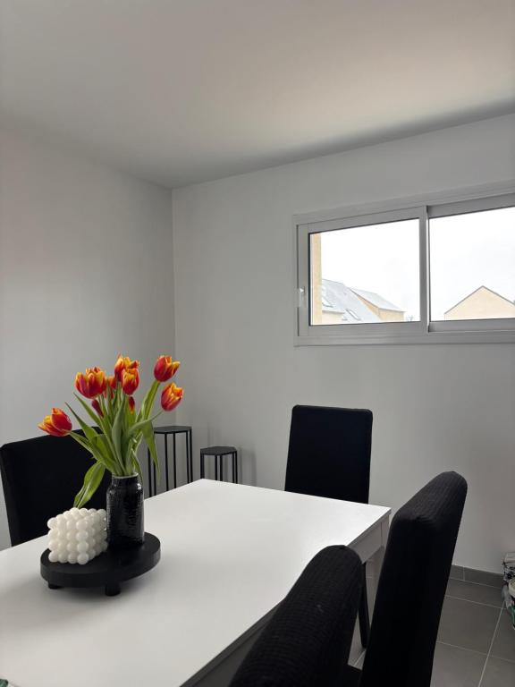 une table blanche avec un vase de fleurs sur elle dans l'établissement Séjour chez l habitant proche circuit des 24h, à Étival-lès-Le Mans