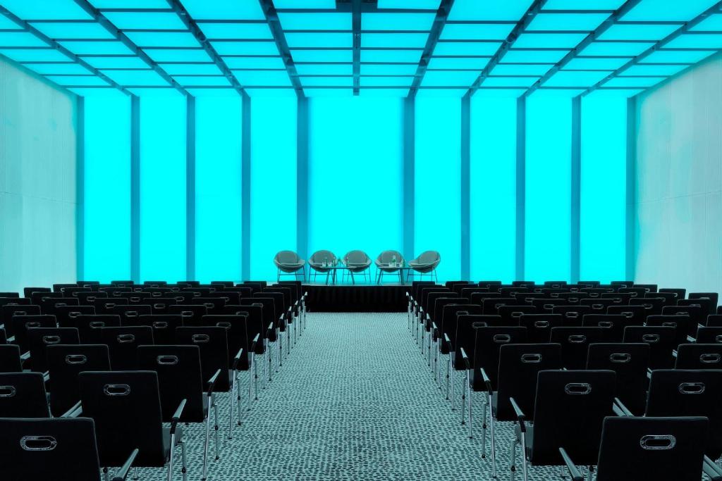 an empty auditorium with black chairs and blue ceilings at Renaissance Warsaw Airport Hotel in Warsaw