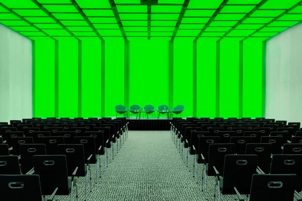 an empty room with black chairs and green screen at Renaissance Warsaw Airport Hotel in Warsaw