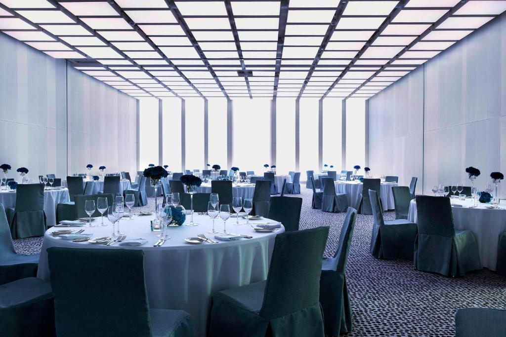 a large room with tables and chairs with white tablecloths at Renaissance Warsaw Airport Hotel in Warsaw