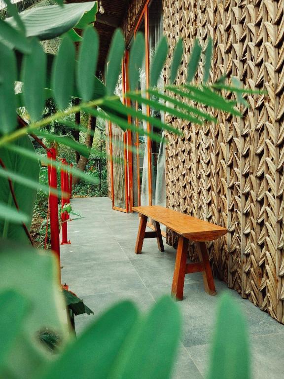 a wooden bench sitting next to a wall at Nông Trại Thảnh Thơi in Ben Tre