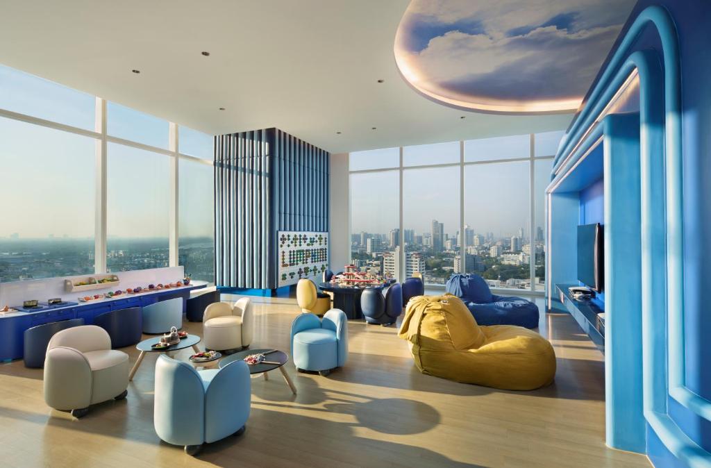 A colorful high-floor lounge with panoramic city windows and playful seating.