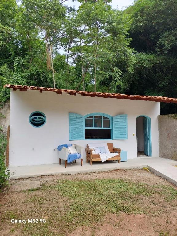 a white house with a blue window and a yard at Charmosa edícula próxima a praia in São Sebastião