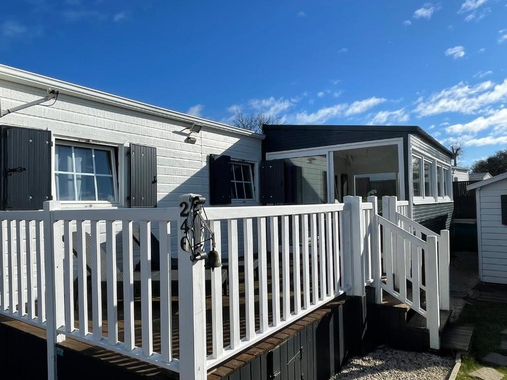 une maison avec une clôture blanche et une terrasse couverte dans l'établissement Mobil home avec piscine sur la côte de granit rose, à Trégastel