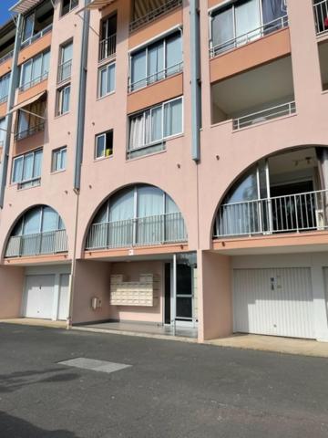 un grand bâtiment rose avec des fenêtres cintrées et une rue dans l'établissement Appartement T2 Cabine Résidence Antinéa au Cap d'Agde proche plage et port secteur Richelieu, au Cap d'Agde