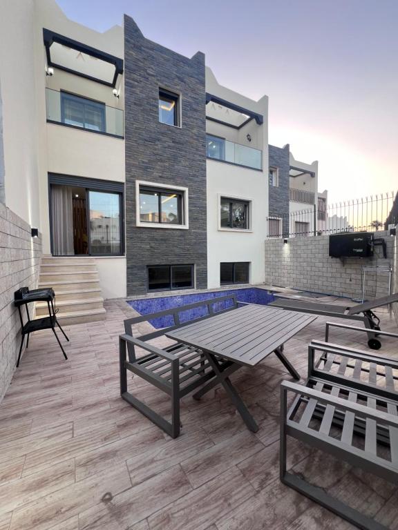 a patio with a table and benches in front of a building at Villa familiale avec piscine in Agadir