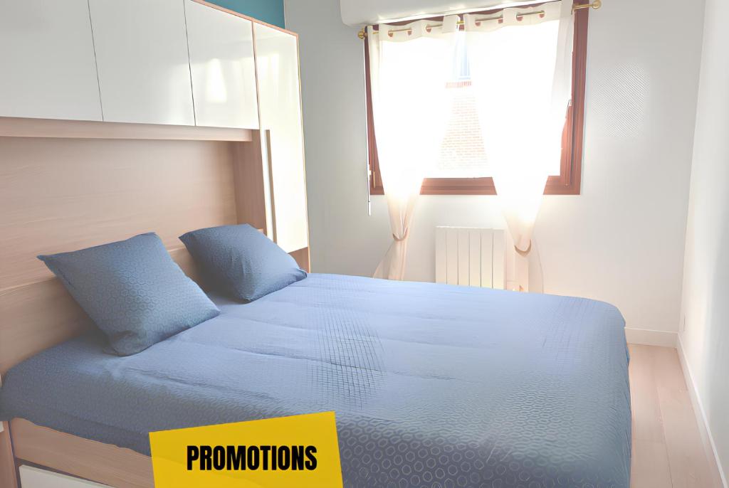 a bedroom with a bed with blue sheets and a window at Paul Sautai - 2 couchages - proche centre in Amiens