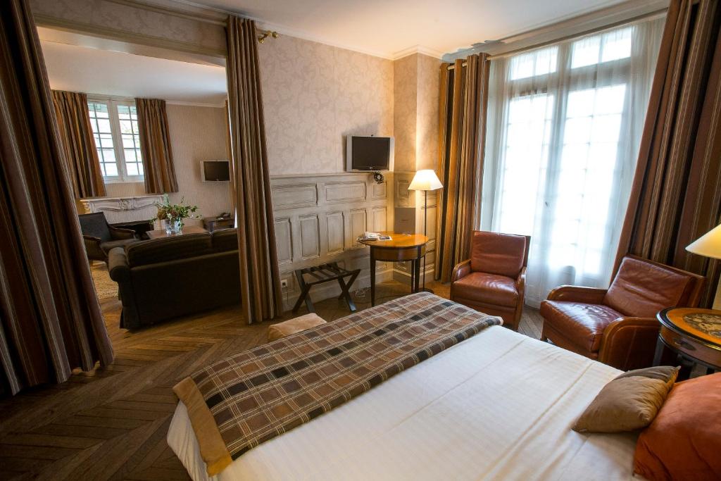 a hotel room with a bed and a living room at Villa Augeval Hôtel de charme & Spa in Deauville