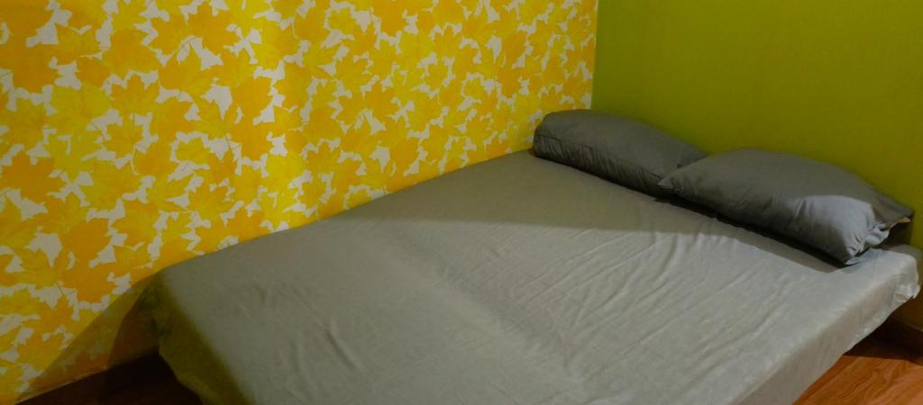 a bed in a room with a yellow wall at Minimalis 2BR Sudirman Suite Apart Bandung by Metta in Bandung