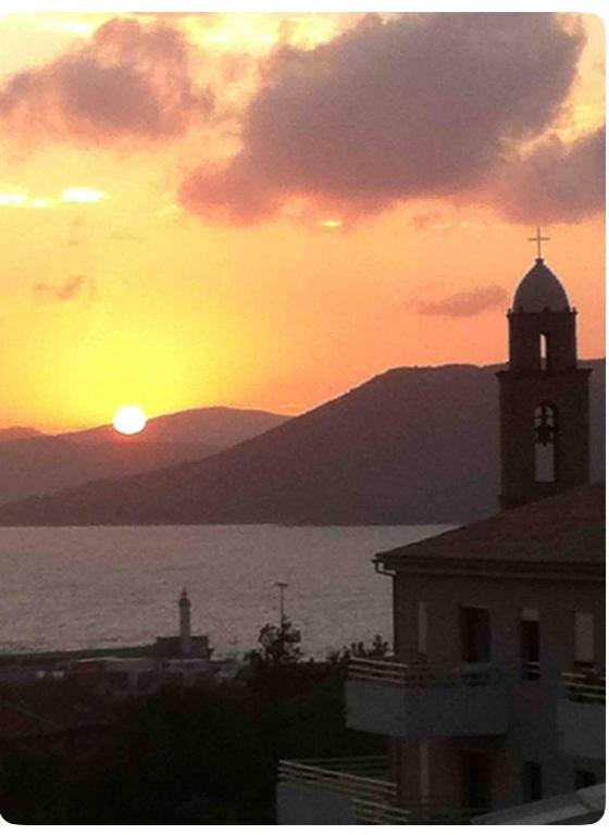 un coucher de soleil sur l'eau avec une tour d'horloge dans l'établissement Propriano appartement vue mer, à Propriano