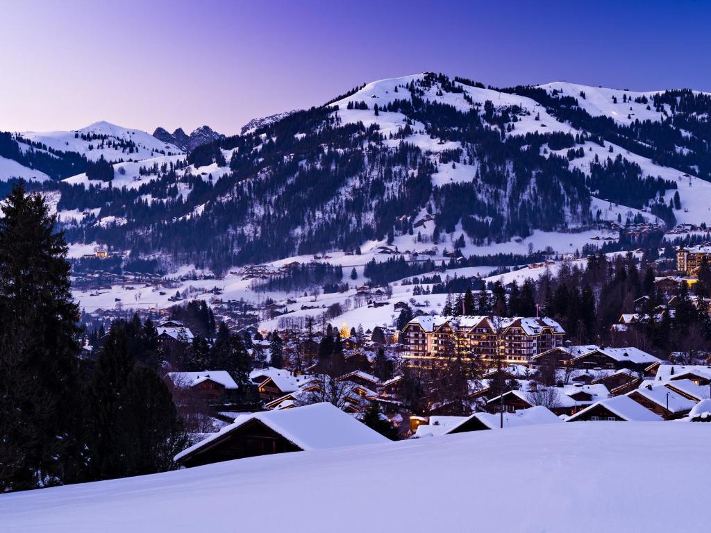 eine schneebedeckte Stadt vor einem Berg in der Unterkunft Park Gstaad in Gstaad