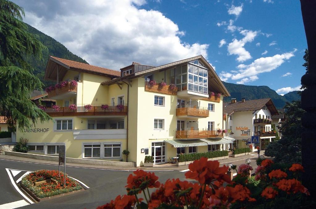a large white building with balconies on a street at Hotel Tannerhof in Schenna