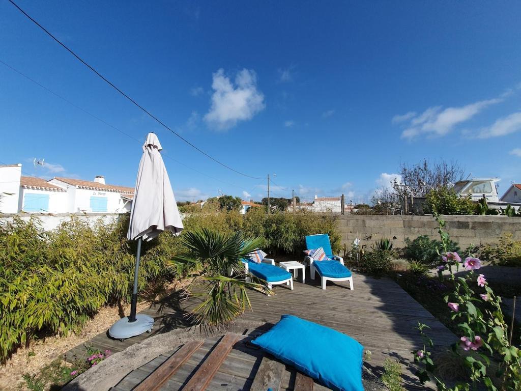 un patio avec deux chaises et un parasol dans l'établissement charmante maisonnette a 400m de la plage, à Noirmoutier-en-l'lle