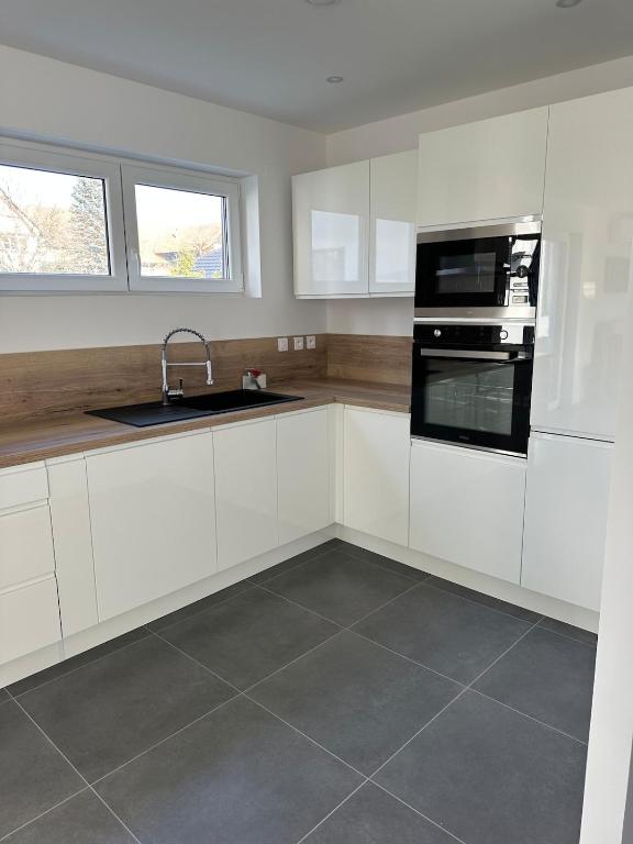 une cuisine avec des armoires blanches et un évier dans l'établissement Le coin de nature paisible, à Wentzwiller