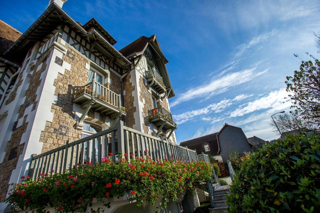 a building with a balcony with flowers on it at Villa Augeval Hôtel de charme & Spa in Deauville
