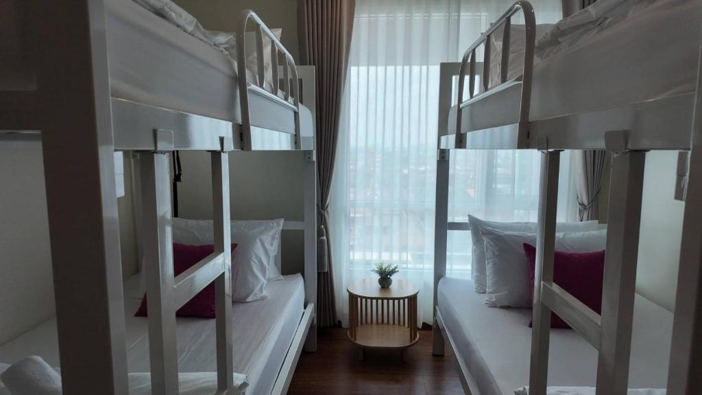 two bunk beds in a room with a window at Kashouse hatyai in Ban Khlong Pleo