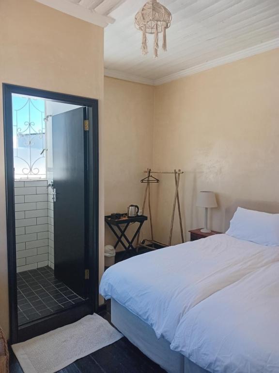 Cozy room in the Heart of Simon's Town في كيب تاون: غرفة نوم بسرير وباب زجاجي