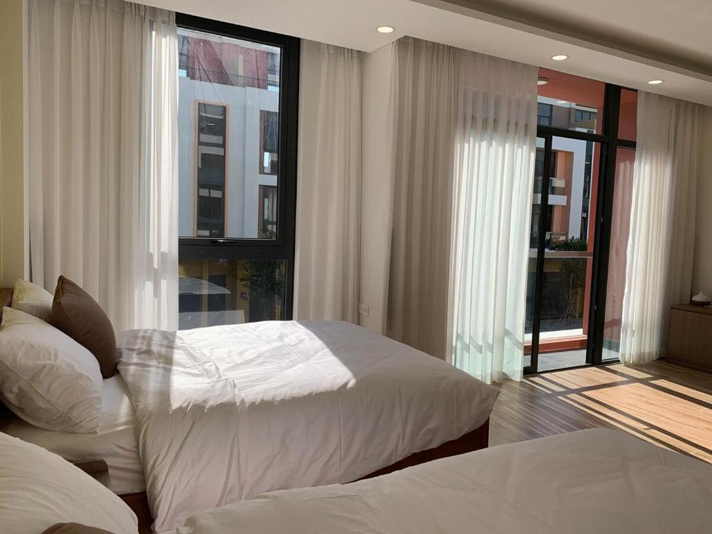 a bedroom with two beds and large windows at Mey lnn Hotel Phu Quoc Island in Phu Quoc