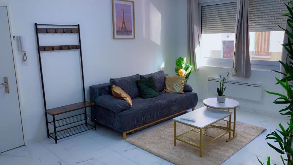 un salon avec un canapé bleu et une table dans l'établissement OT Appart City Logement élégant et central, à Clermont-Ferrand