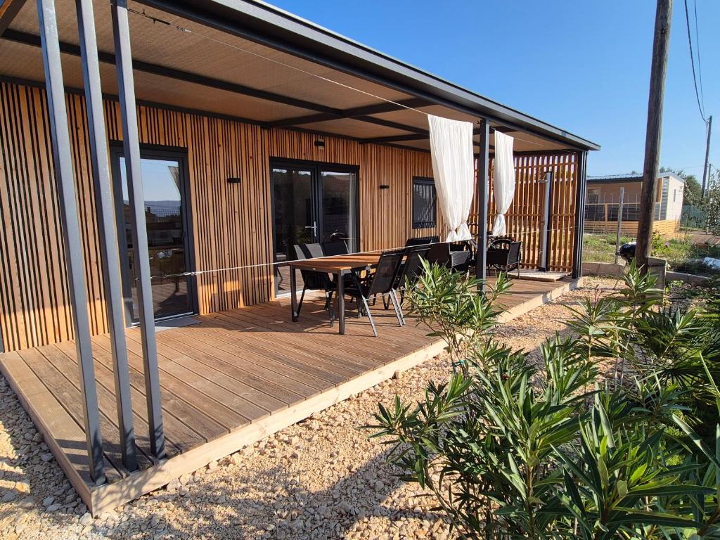 a house with a wooden deck with a table and chairs at Hiška Morska ravnica in Sveti Petar