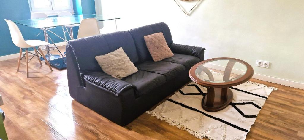 - un canapé noir dans le salon avec une table dans l'établissement Appartements Marseille cours Julien, à Marseille