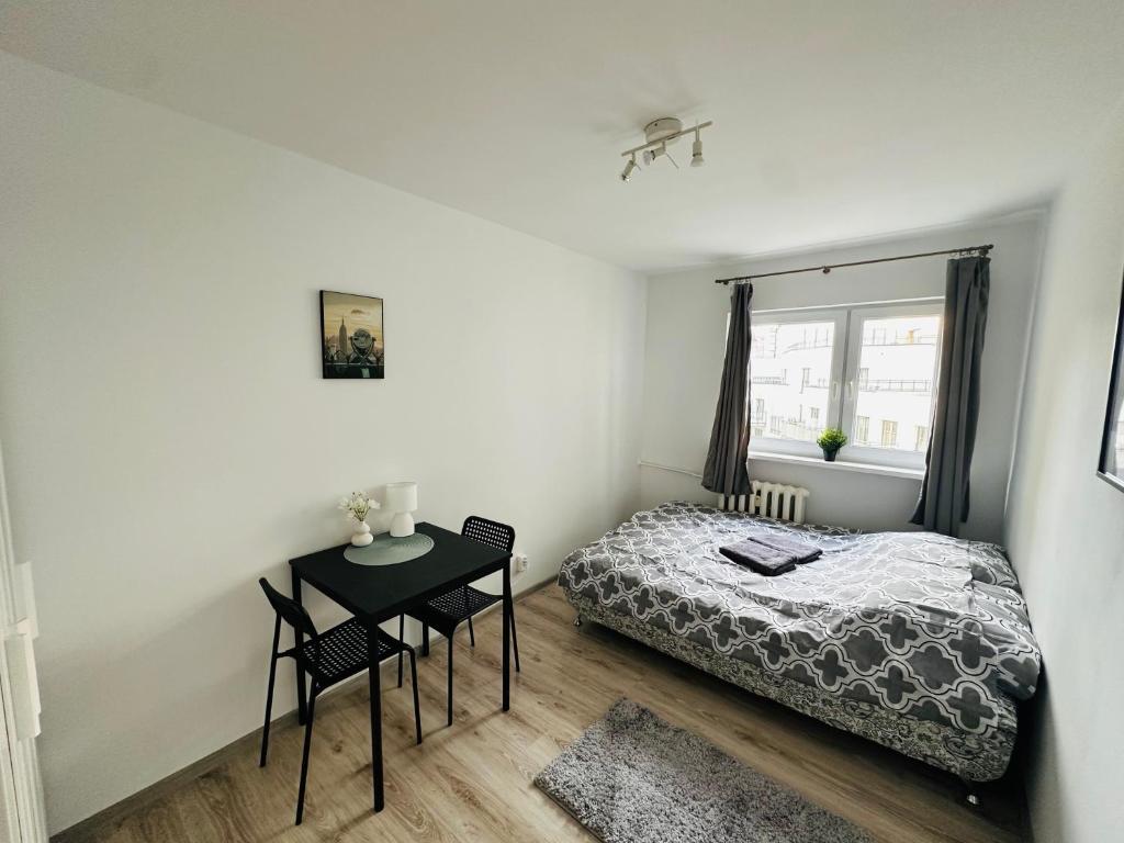 a bedroom with a bed and a table and a window at Wola Ratusz Rooms in Warsaw