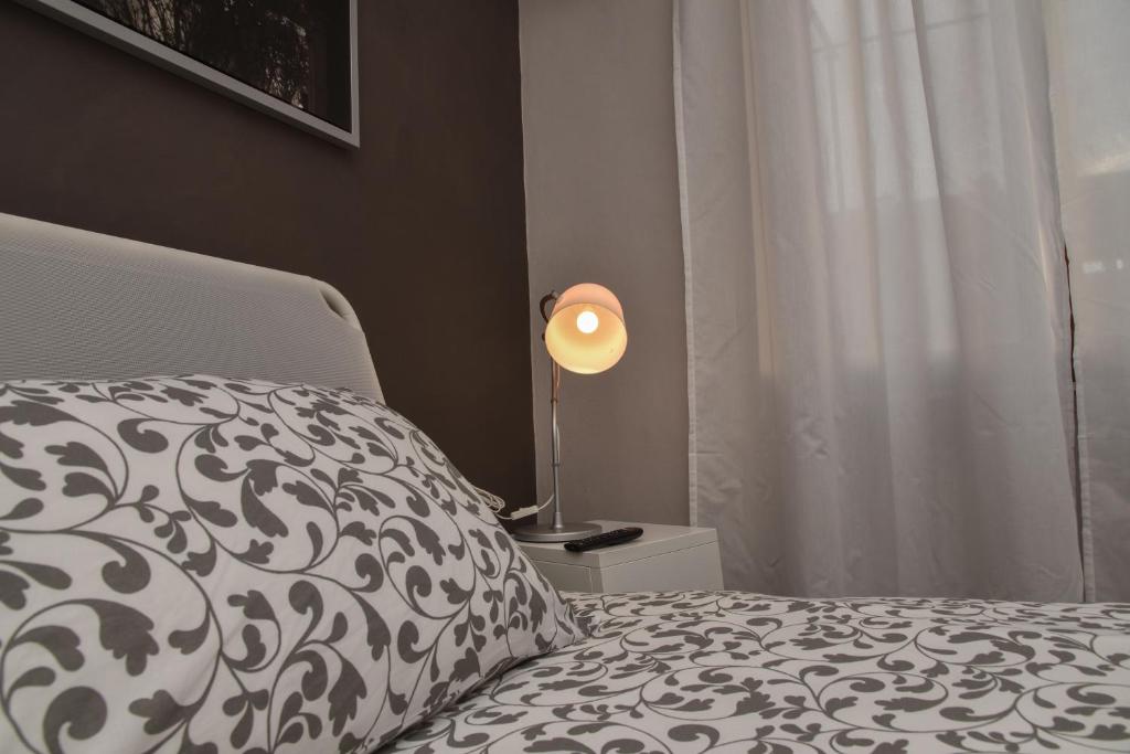 een slaapkamer met een bed en een lamp op een nachtkastje bij L'Agrifoglio Affittacamere in Gattinara