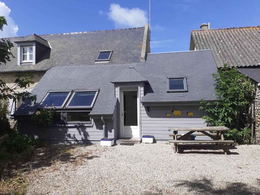 une maison avec une table de pique-nique devant elle dans l'établissement GITE LES MOUETTES MAISON A 300m de la MER, à Pirou