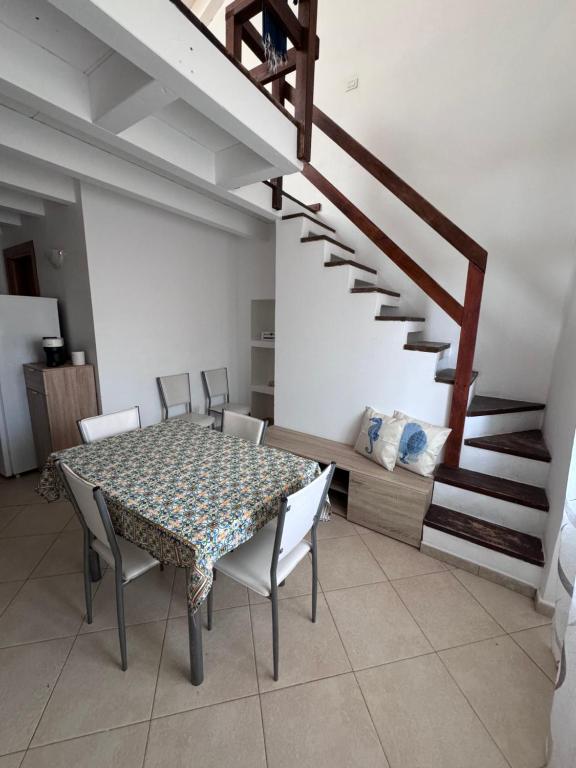 a dining room with a table and chairs and a staircase at Il Nido in Lampedusa