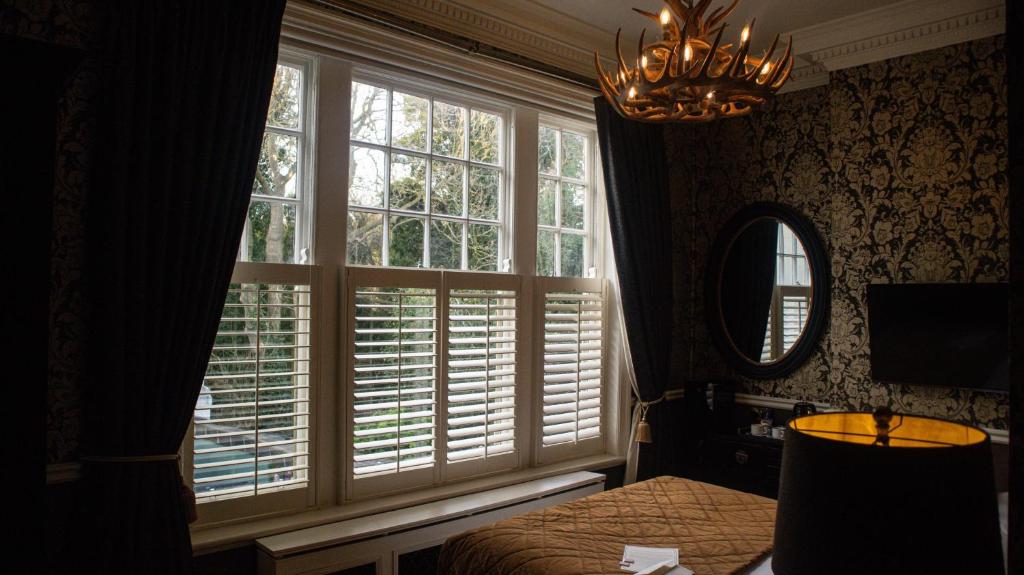 a bedroom with a window with blinds and a mirror at 40 Winks Hospitality in Durham