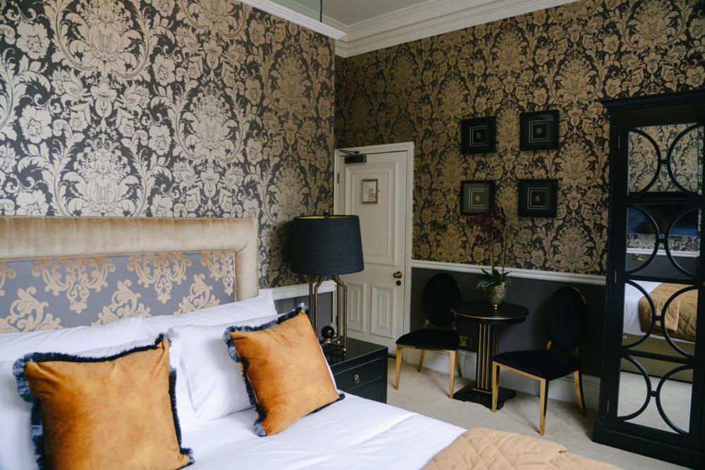 a bedroom with a bed and a wall with wallpaper at 40 Winks Hospitality in Durham