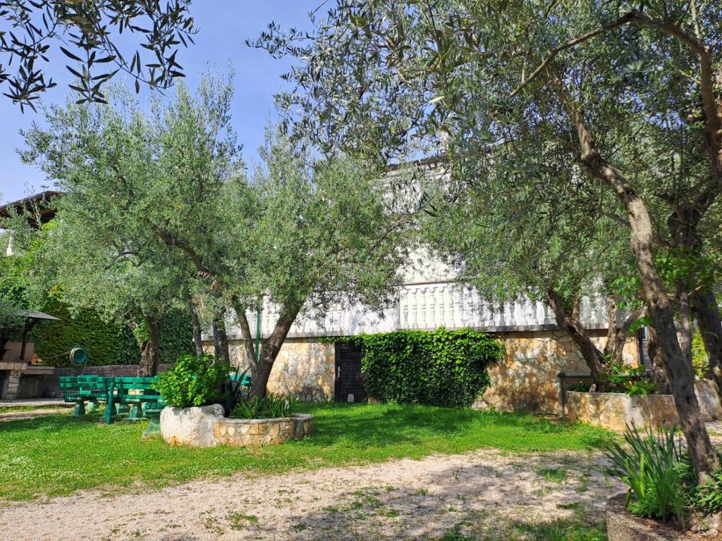 a stone building with trees and a green bench at Bernarda in Sveti Vid-Miholjice