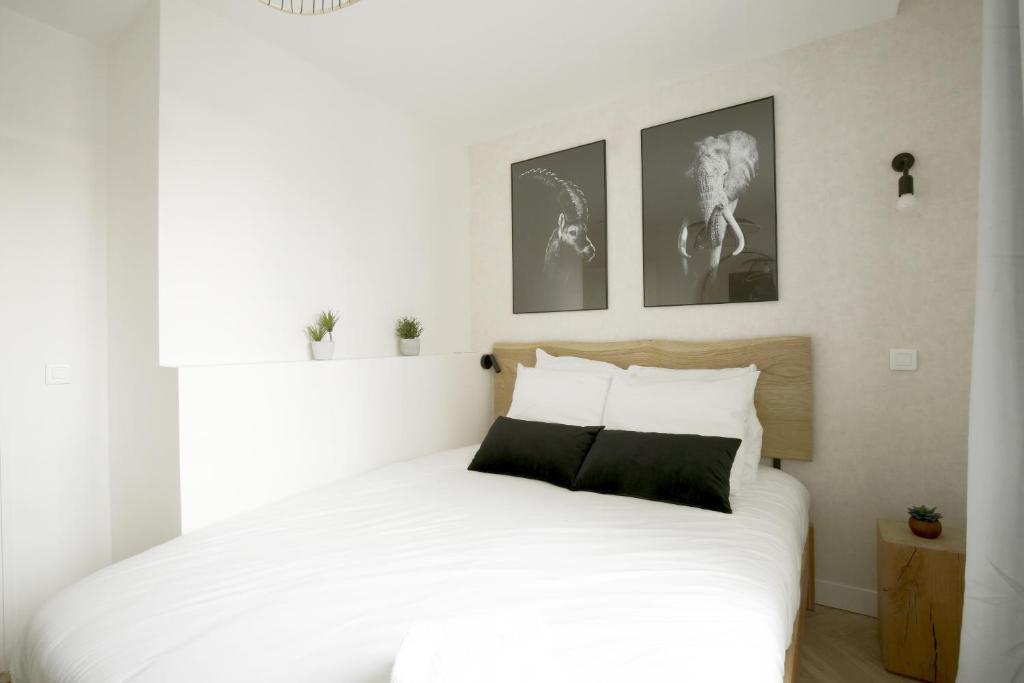 une chambre avec un lit blanc avec deux tableaux au mur dans l'établissement Relish Best Paris Baguette in Light-Filled Duplex, à Paris