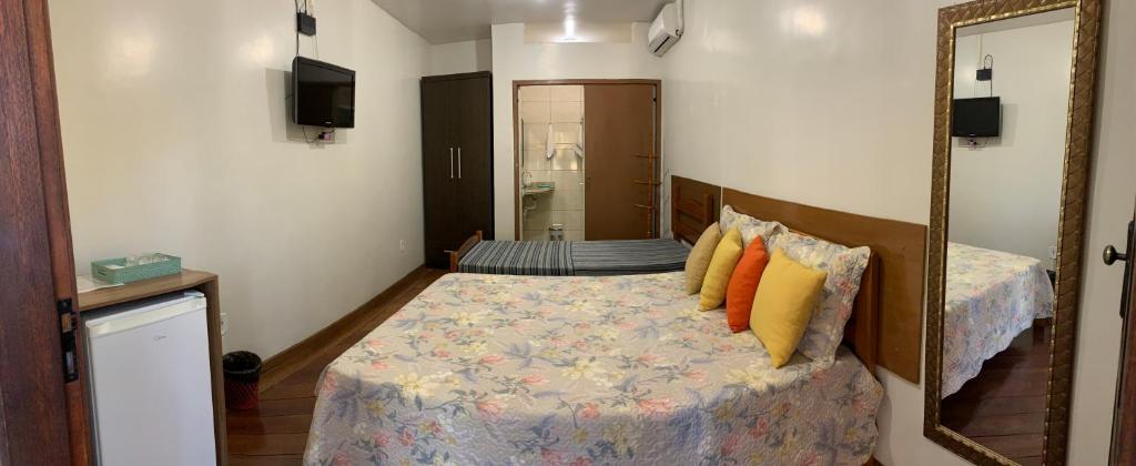 a small bedroom with a bed with a mirror at Suites Arraial do Cabo in Arraial do Cabo