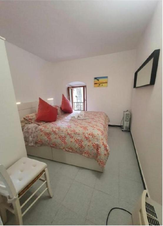 a bedroom with a bed with red pillows and a chair at Casa caterina in Corniglia