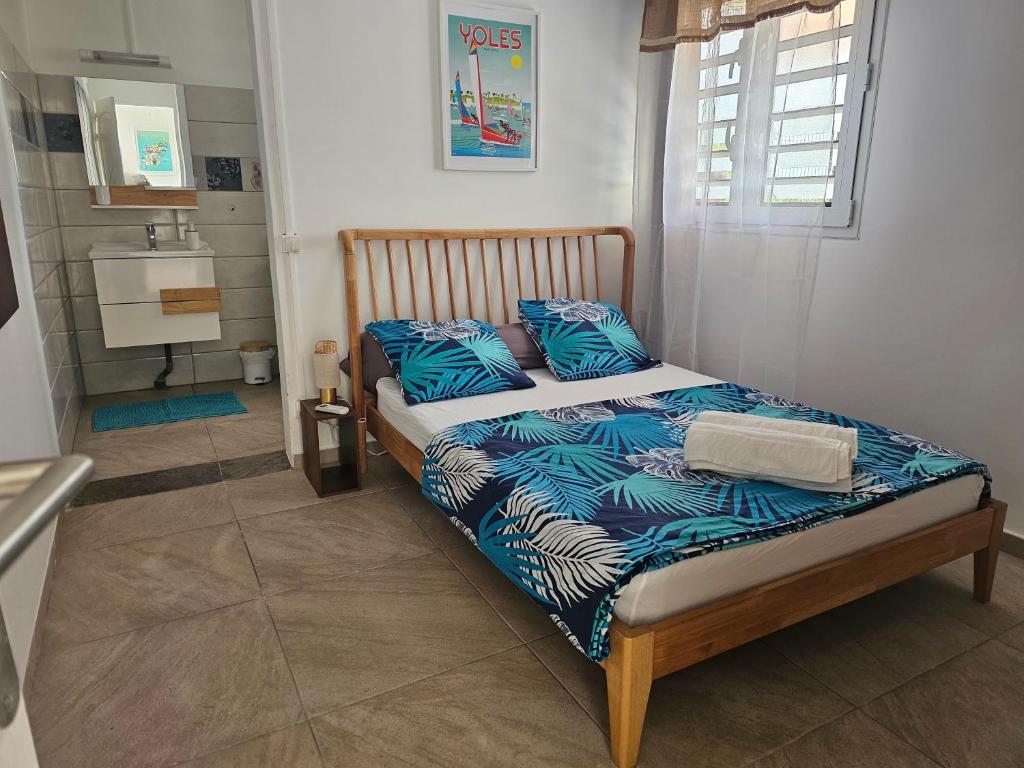 a bed with blue pillows in a small room at Appartement Bleu Corail avec Jacuzzi in Les Trois-Îlets