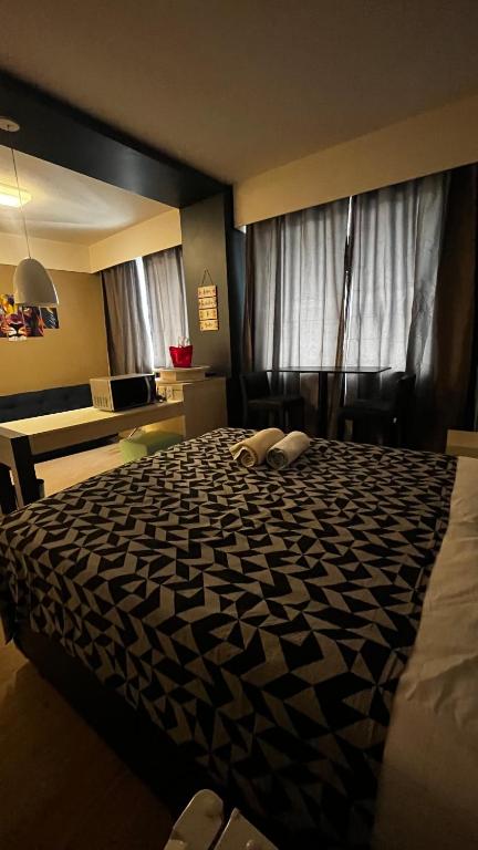 a bedroom with a bed with a black and white comforter at FLAT NO CORAÇÃO De ALPHAVILLE in Barueri