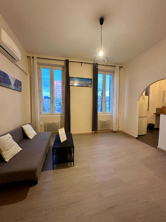 un salon avec un canapé et quelques fenêtres dans l'établissement Joli Appartement aux Chartreux - Calme & lumineux, à Marseille