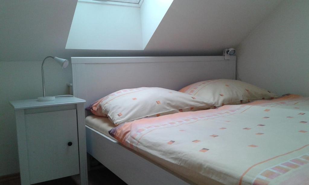 a bed with two pillows and a lamp on a table at Apartment Olomouc in Olomouc