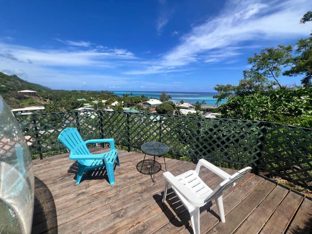 two chairs and a table on a deck with the ocean at Maharepa Lodges Vue sur les étoiles in Maharepa