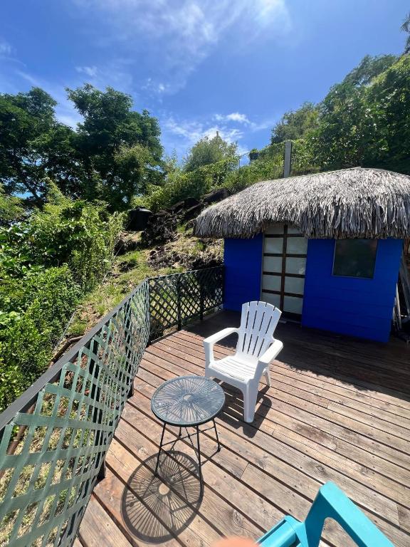 a deck with a chair and a table and a hut at Maharepa Lodges Vue sur les étoiles in Maharepa