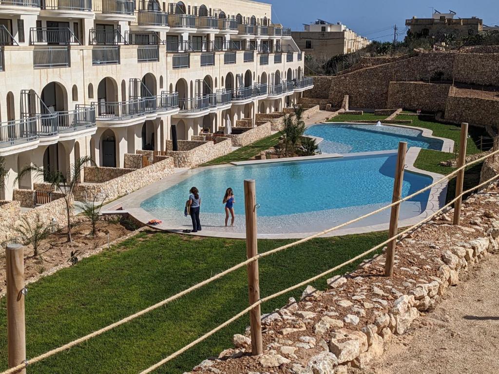two people standing next to a swimming pool next to a building at Hal Wardija Sunny Retreat in Qala