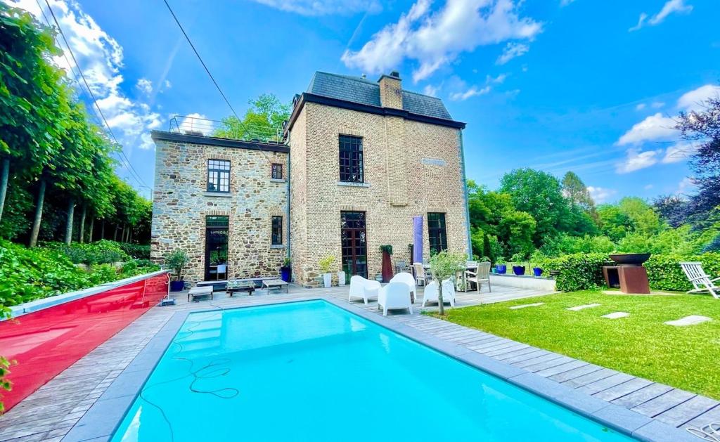 a house with a swimming pool in front of a building at Le Clos du Châtelain, in Profondeville