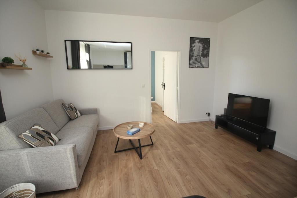 un salon avec un canapé et une table dans l'établissement charmant 2 pièces, à Cormeilles-en-Parisis