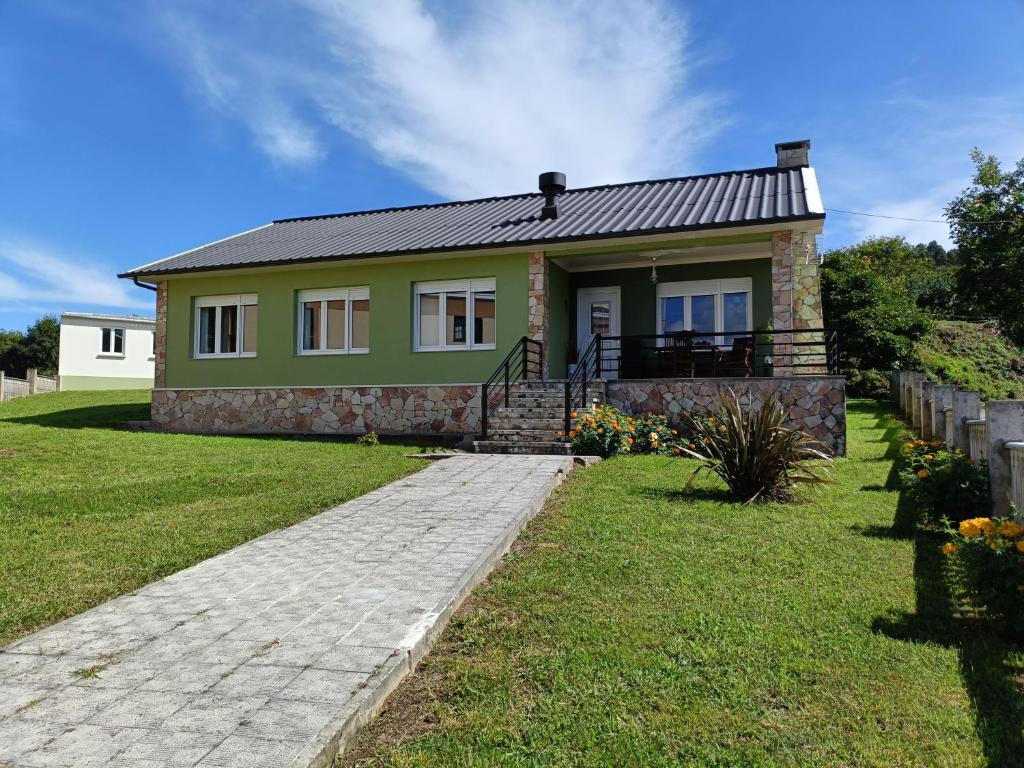 a green house with a stone walkway in front of it at Casa do Olmo in Porto de Espasante